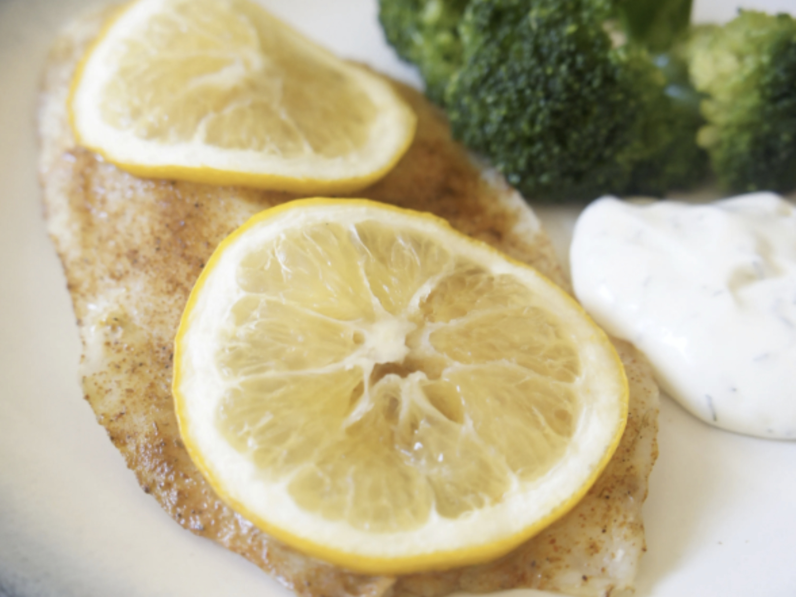 tilapia fillet with lemon slices and side of broccoli