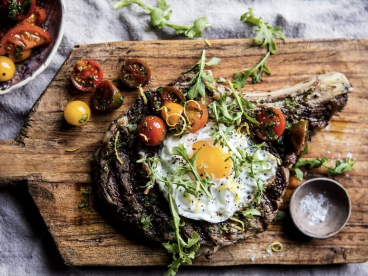 tuscan steak with egg and cherry tomatoes on a cutting board