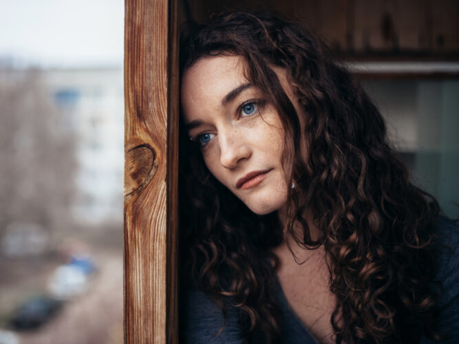 woman looking sad outside cold window