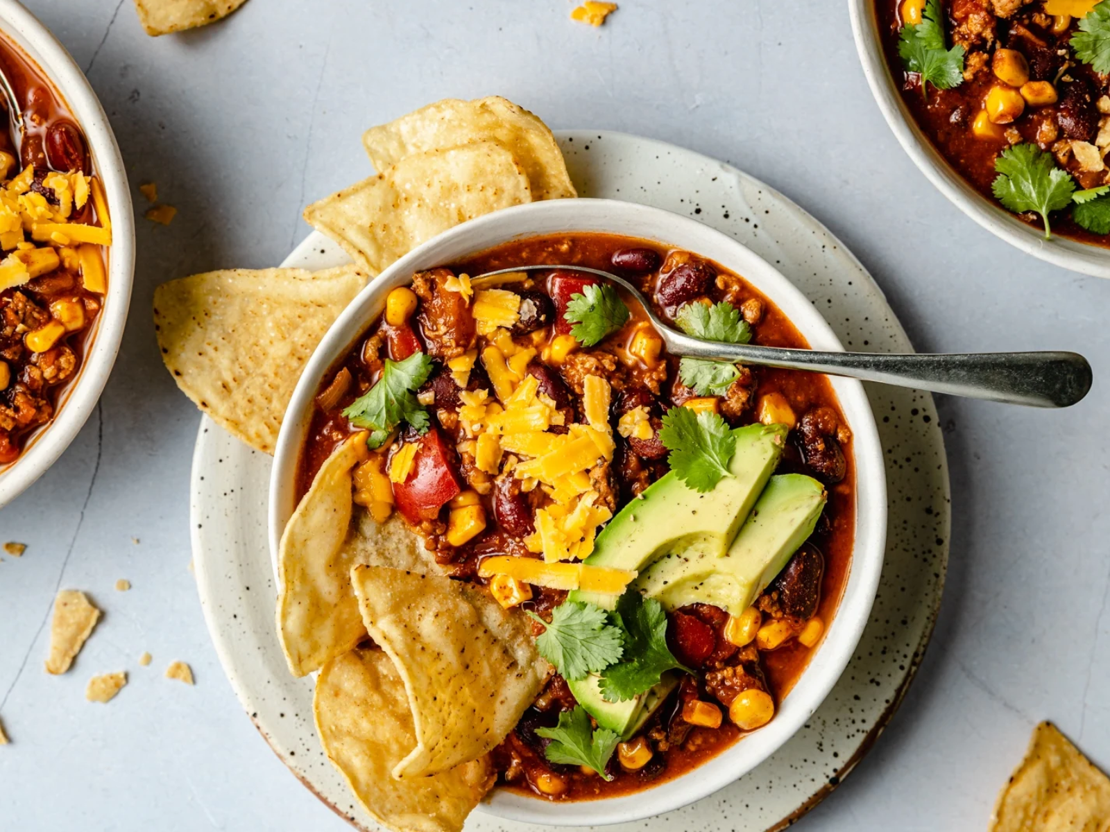 turkey chili with avocado slices cheese and tortilla chips