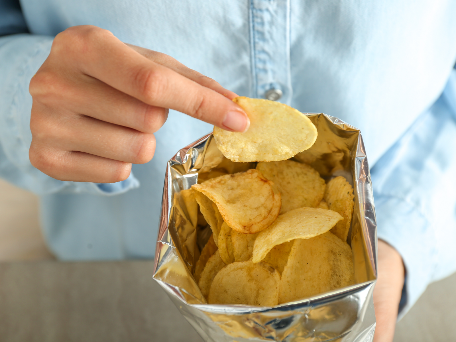 woman reaching into a bag of chips