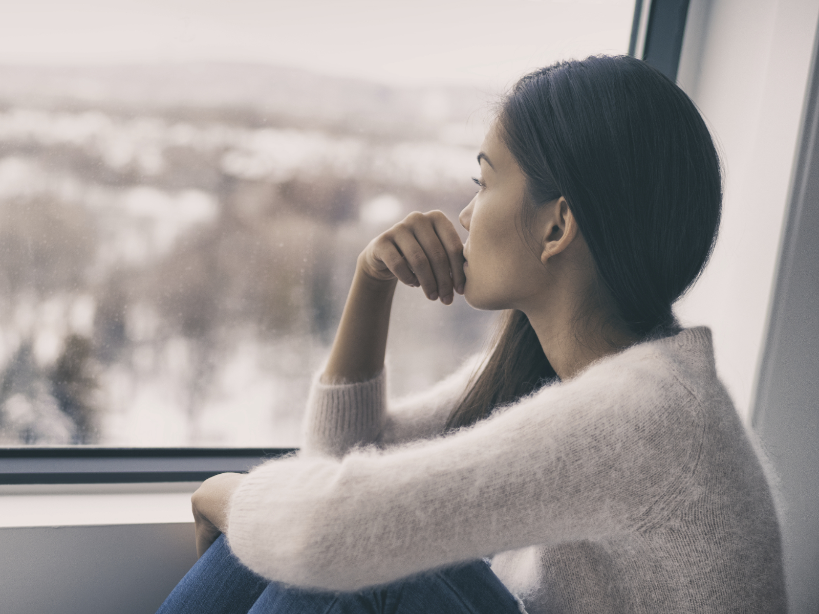 woman staring outside a window during the winter