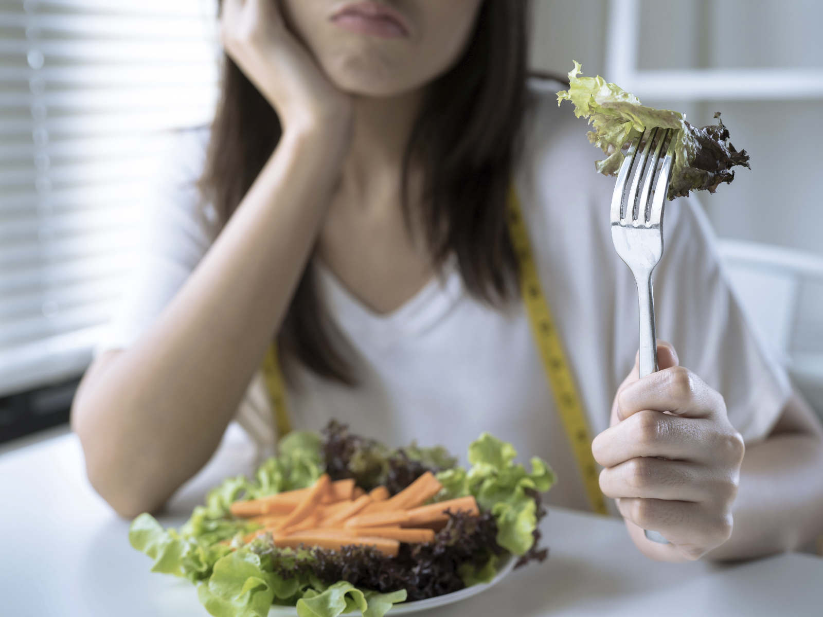woman unhappy eating salad